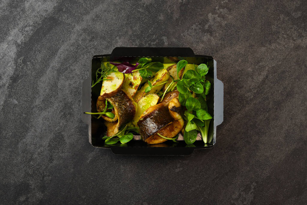 Fish mackerel baked with potato and lettuce. Healthy food, restaurant dish delivery. Top view. Free space for your text. Dark background. - Foto, Imagem