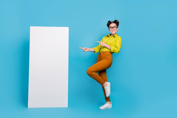 Full body portrait of cheerful lady direct finger empty space large phone banner isolated on blue color background - Fotografie, Obrázek