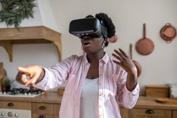 African woman in pink clothes in vr glasses looking excited - Photo, Image