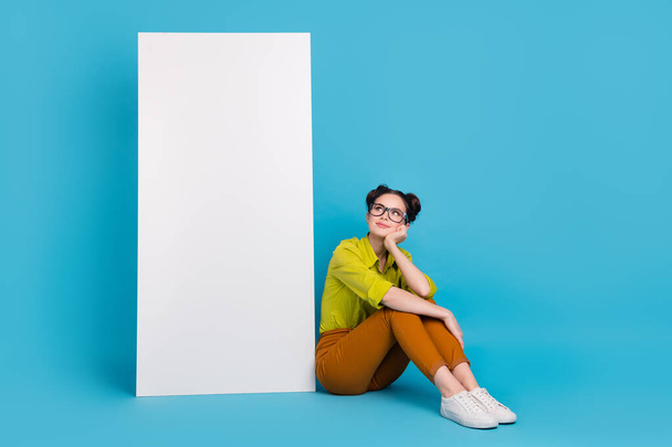 Full body photo of minded smart person sit floor look empty space announcement isolated on blue color background - Foto, Imagem