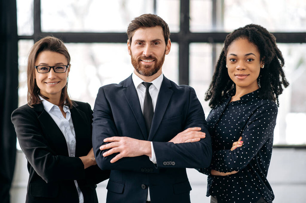 Successful multiracial influential business team, people look at the camera, smiling. Elegant creative colleagues stand in modern office, show confidence and success, teamwork, collaboration concept - Фото, изображение