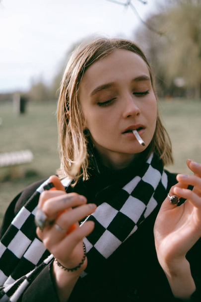 Porträt eines Mädchens, das im Park sitzt und fröhlich Marihuana raucht - Foto, Bild