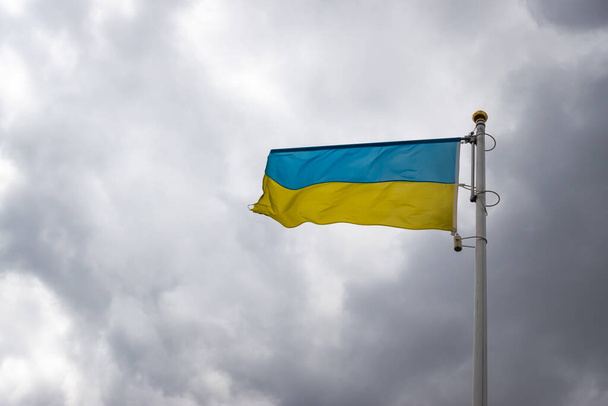 Ukrainian banner wave on the background of cloudy, dramatic sky. Picture taken in the day, sky full of clouds.   - Photo, image