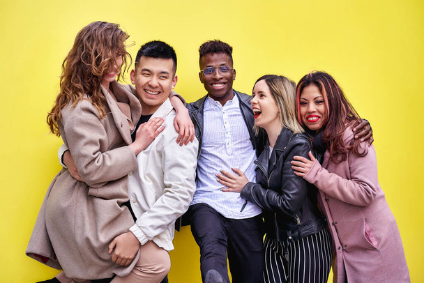 Junge Menschen mit mehreren Rassen amüsieren sich auf gelbem Hintergrund. Gruppe von Freunden verschiedener Ethnien.  - Foto, Bild