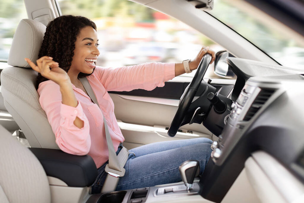 Happy black woman enjoying music driving luxury car - Foto, Bild