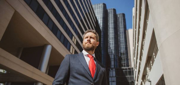 Executive businessman. Portrait of ceo near modern office in suit. Happy leader standing in front of company building. - 写真・画像