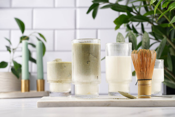Wysoka szklanka falowana z matcha latte - japońska zielona herbata w proszku i bita mleko na marmurowej desce w białej kuchni - Zdjęcie, obraz