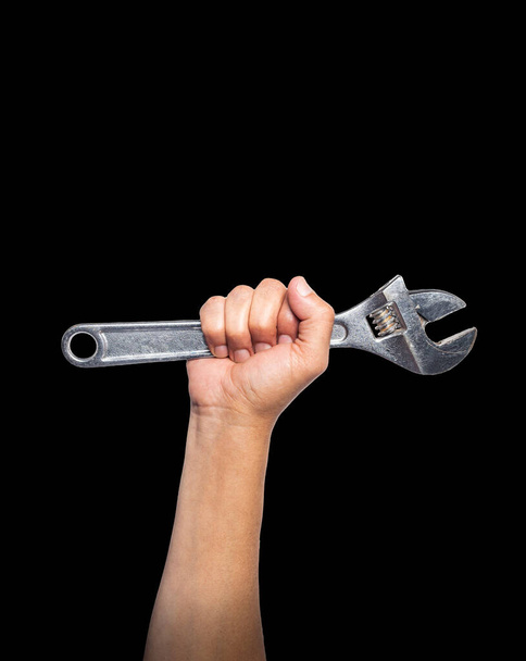 Arm of a man showing muscle gripping a pipe wrench on a black background. Labor day concept - Foto, Imagen