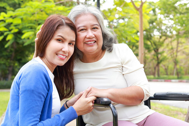 Elderly mother and daughter smiling happily in the park in the morning. Family concept. Health care for the elderly in retirement age. Nurses take care of the elderly. Close-up photo. - Foto, immagini
