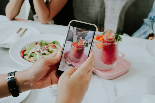 Χρησιμοποιώντας ένα smartphone για να φωτογραφίσει τρόφιμα και ποτά. - Φωτογραφία, εικόνα