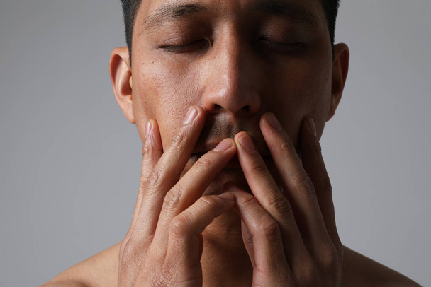 Close-up of Asian man with closed eyes and touching his face. Mental issues. - Photo, Image