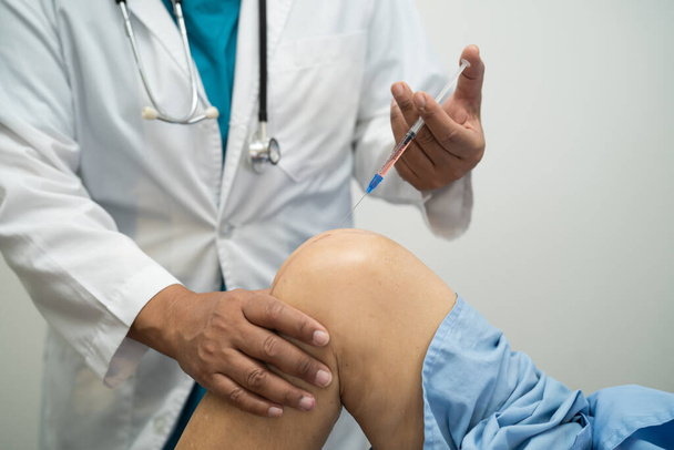 アジアの医師は痛みなしで歩くために高齢女性の膝の中にヒアルロン酸血小板豊富な血漿を注入します. - 写真・画像