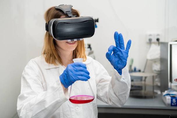 Female scientist show sign OK in VR glass, playing metaverse NFT game  - Photo, Image
