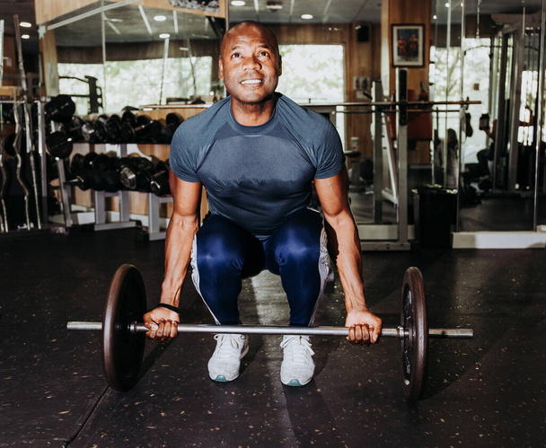 Stockfoto van een zwarte man die push-ups doet met een gewichtsbalk. Sport en vrije tijd - Foto, afbeelding