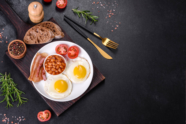 Англійський сніданок з смаженими яйцями, беконом, бобами, помідорами, спеціями і травами. Гарний і поживний початок дня - Фото, зображення