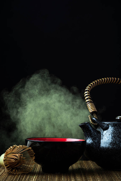 Abbina la cerimonia del tè verde. Teiera, frusta e spruzzi su sfondo scuro. - Foto, immagini