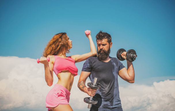 Sporty couple with dumbbell outdoors. Couple working out with dumbbells. Fitness club outside on sky. - Foto, afbeelding