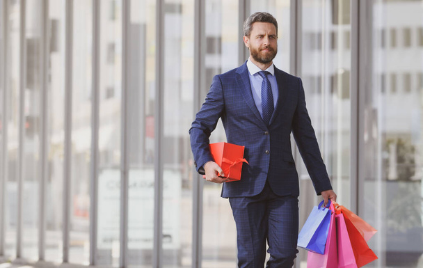 Business man holding shopping bags and walking in shopping store. Shopping and paying. Shopaholic shopping concept. - Φωτογραφία, εικόνα