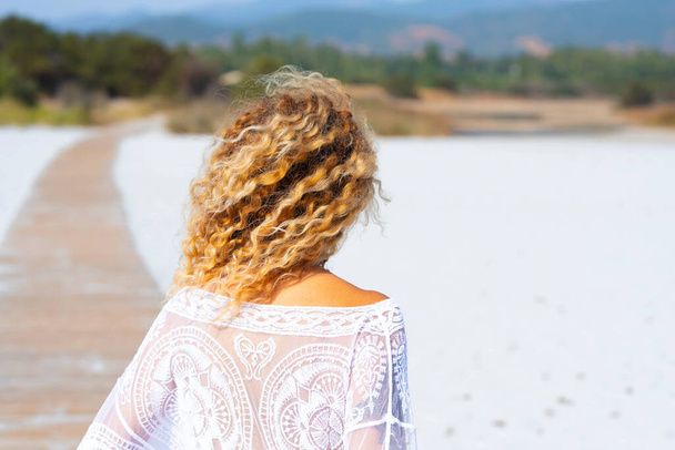Vue arrière des vagues de surf blondes coiffure, femme profitant de la plage en vacances d'été. Concept de tourisme et de tourisme dans la nature. Femmes marchant sur le sable en plein air - Photo, image