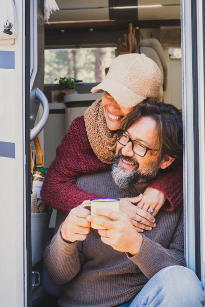 Vertical image of tourists with camp van vehicle. Adult man and woman enjoying nature and travel lifestyle. Van life with modern motor home. People smiling and having fun with love on vacation - 写真・画像