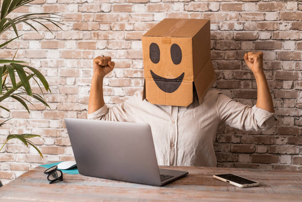 Επιχείρηση και επιτυχία στην εργασία με το laptop. Οι άνθρωποι με χάρτινο κουτί χαμόγελο στο κεφάλι γιορτάζουν και αγαλλίαση μπροστά από έναν υπολογιστή. Νέοι επιχειρηματικοί στόχοι. Κρυπτο ιδιωτικότητα και ανώνυμη ιδέα σέρφινγκ. Έχω ιδέα. - Φωτογραφία, εικόνα