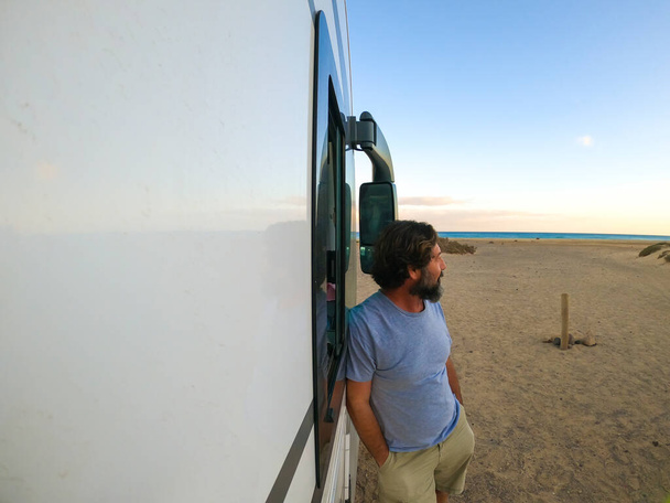 Kypsä mies seisoo modernin matkailuauton ulkopuolella ihaillen merta ja nauttien rannasta. matkustaa ihmisten elämäntapa käsite. Vapausleirintäalue. Aikuisten katse horisonttiin ja luontoon - Valokuva, kuva