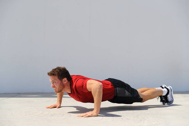 Pushup fitness man doing push-up bodyweight exercise on gym floor. Athlete working out chest muscles strength training outdoors - Фото, зображення