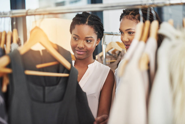 Beslissingen, beslissingen... Gesneden foto van twee vrouwen die naar kleren keken op een reling in een winkel.. - Foto, afbeelding