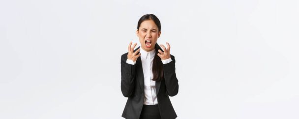 Божевільний генеральний директор сердитий на співробітників. Розлючена азіатська жінка-менеджер стискає руки в кулаки, кричить і похмуро розлючується, стоїть сперма на білому тлі
 - Фото, зображення