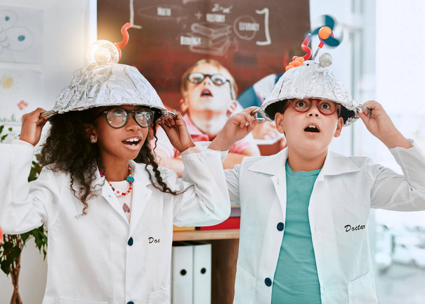 Were well known for our bright ideas. Shot of two adorable young school pupils doing an experiment about electricity and light in science class at school. - Photo, Image