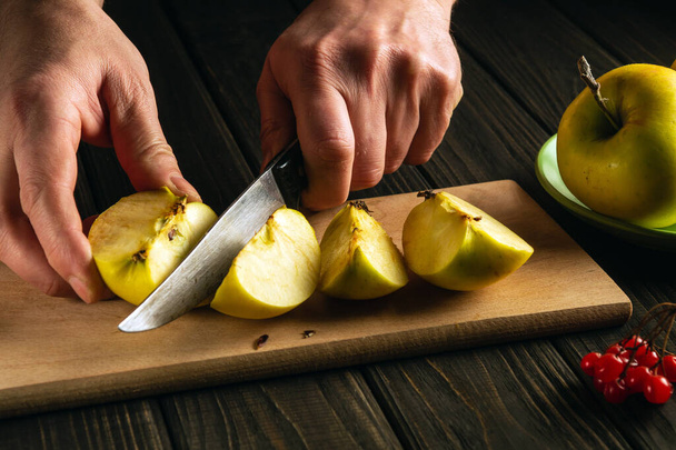 Chef hands with a knife cut fresh apples on a wooden cutting board. Apple diet idea - Foto, Bild