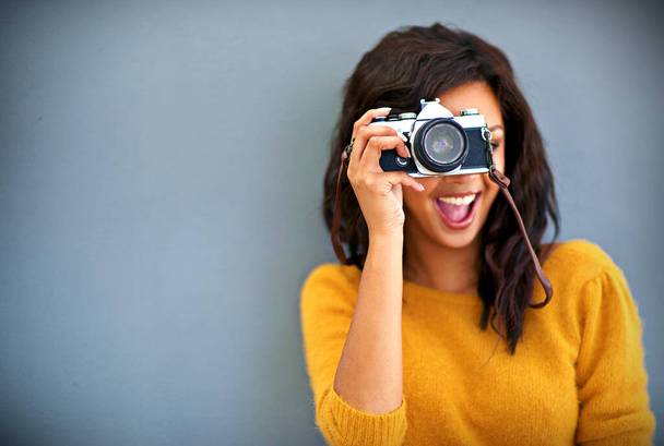 Wesołego dnia. Studio portret młodej kobiety korzystającej z zabytkowej kamery na szarym tle. - Zdjęcie, obraz