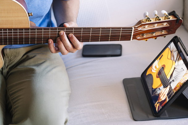 Adult man studying guitar online with tablet at home. - Foto, imagen