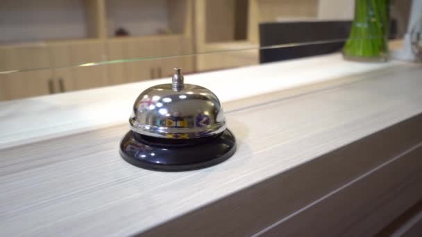 A woman's manicured hand rings the bell at the hotel reception. The metal bell reflects the Georgian flag or the red and white flag. The tourist's hand hits the bell at the hotel. - Metraje, vídeo