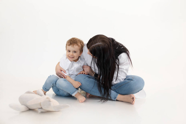 Studio shot of two people, woman and boy having fun and cuddling, talking to each other. Smiling child boy near mother - Photo, Image