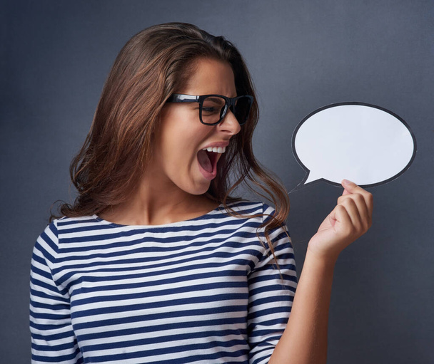 I said no. Studio shot of an attractive young woman holding a blank speech bubble and shouting against a gray background. - Photo, image