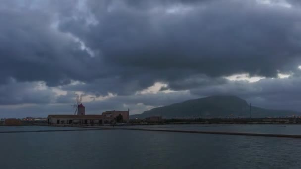 Timelapse zachmurzonego wschodu słońca w młynie soli na zachodnim wybrzeżu Sycylii, Saline di Trapani, Włochy - Materiał filmowy, wideo