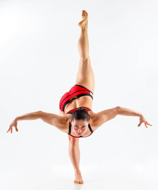 Sportieve mooie jonge vrouw beoefenen van yoga, doen lunge oefening, Revolved Side Angle Pose,, trainen uit het dragen van rode en zwarte sportkleding, studio volledige lengte, geïsoleerde witte achtergrond.  - Foto, afbeelding