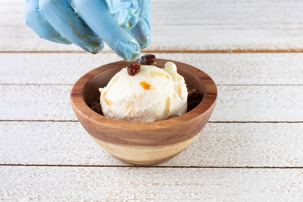A closeup view of a hand placing toppings on a scoop of ice cream. - Foto, immagini