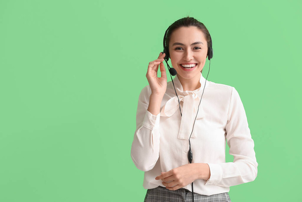 Krásná mladá podnikatelka se sluchátky na zeleném pozadí - Fotografie, Obrázek