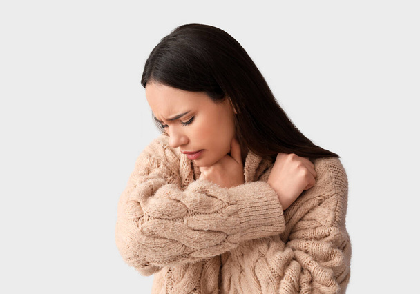 Jonge vrouw lijdt aan zere keel op witte achtergrond - Foto, afbeelding