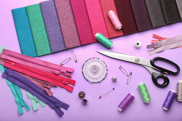 Set of colorful zippers and sewing supplies on purple background - Foto, afbeelding