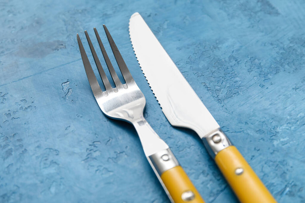 Silver knife and fork on blue background, closeup - Foto, Imagem