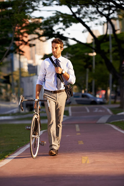 Keeping his carbon footprint as low as possible. Shot of a businessman commuting to work with his bicycle. - Foto, Imagem