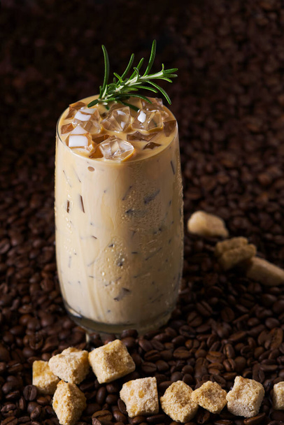 Mrożona kawa latte. Filiżanka mrożonej kawy latte, herbata mleczna na tle ciemnych nasion kawy - Zdjęcie, obraz