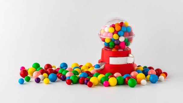 A plastic toy gum ball machine filled and surrounded by gum balls. - Photo, Image