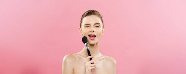 Beauty Concept - Closeup Mulher branca bonita aplicando maquiagem com escova de pó cosmético. Pele perfeita. Isolado em fundo rosa e espaço de cópia
. - Foto, Imagem