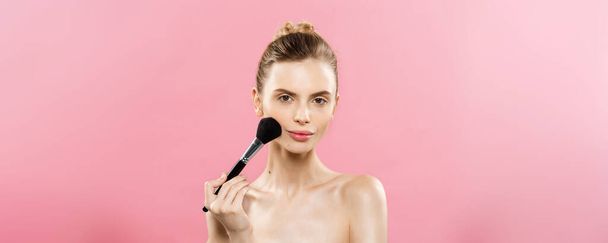 Beauty-Konzept - Nahaufnahme schöne kaukasische Frau Make-up mit kosmetischen Puderpinsel auftragen. perfekte Haut. isoliert auf rosa Hintergrund und Kopierraum. - Foto, Bild