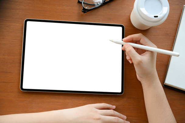 Powyżej kobieta trzymająca rysik i rysująca na ekranie tabletu cyfrowego. makieta z białym ekranem tabletki. - Zdjęcie, obraz