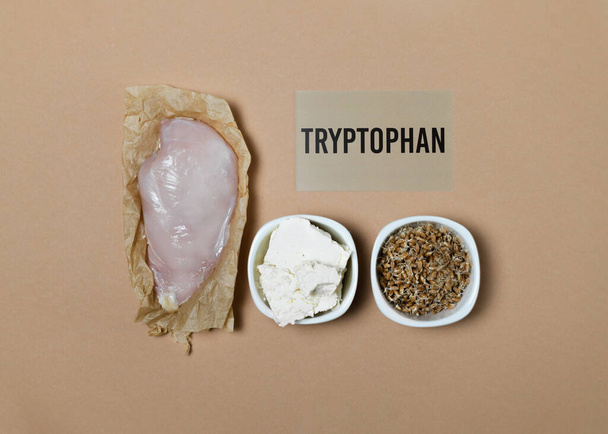 Tryptofan bogate jedzenie. Naturalnymi źródłami tryptofanu są filet z kurczaka, ser wiejski, kiełkowane ziarna pszenicy. Znak kartonowy z napisem. - Zdjęcie, obraz